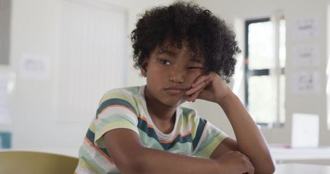 Teenage African American Boy Looking Pensive at Desk in Classroom Natural Light