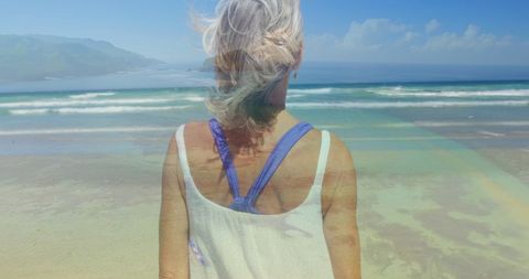 Serene Coastal Moment: Elderly Woman Facing Ocean Waves