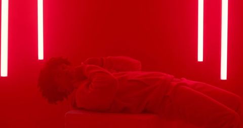 Man reclining in red neon installation
