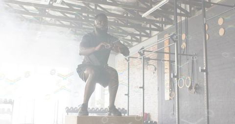 Male athlete jumping and landing on wooden plyo box in industrial gym with chalk dust