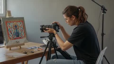 Woman Photographer Shooting Artwork on Tripod Using Window Light in Small Studio