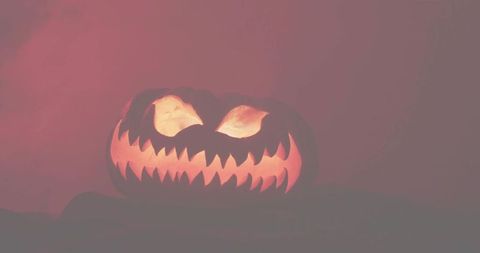 Glowing jack-o'-lantern with jagged teeth and crimson low-key halloween mood