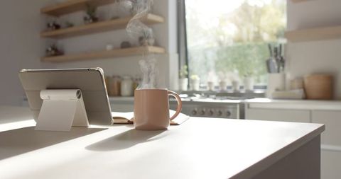 Cozy morning kitchen with tablet and steaming mug