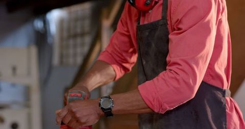 Craftsman using sander on wood in workshop