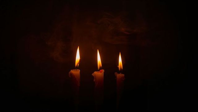 Moody trio of flickering taper candles glowing with warm flames and melting wax drips