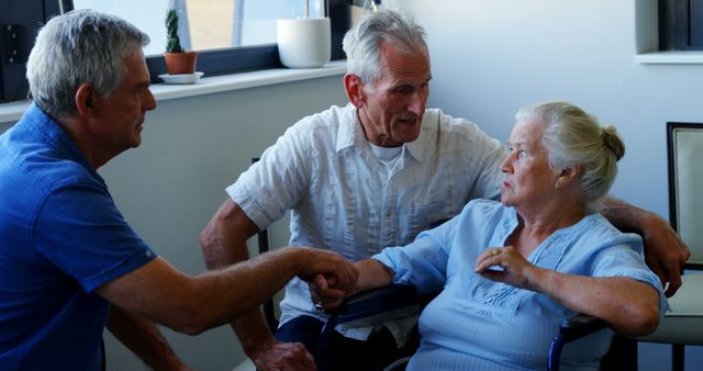 Two senior Caucasian men are assisting a senior Caucasian woman, in a home or care facility setting. Their interaction suggests a moment of care or support, emphasizing the importance of assistance and companionship in later years.