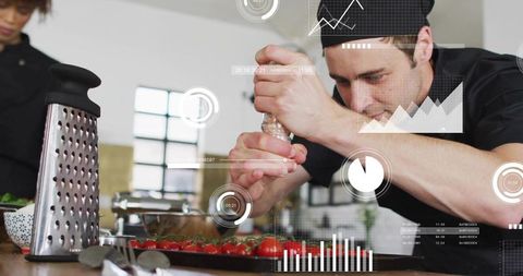 Professional chef seasoning cherry tomatoes with grinder during busy kitchen prep