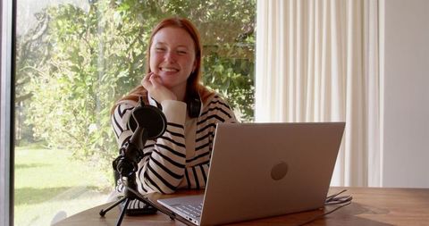 Woman Podcasting From Home Using Laptop Microphone and Headphones