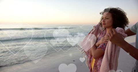 Romantic Couple Embracing on Beach at Sunset with Digital Hearts