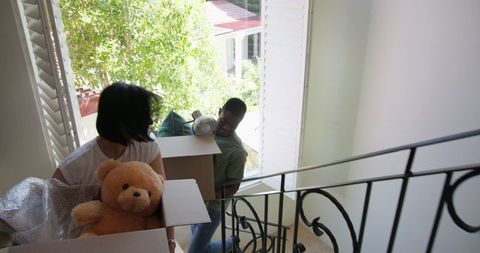 Couple carrying boxes upstairs: moving into new home