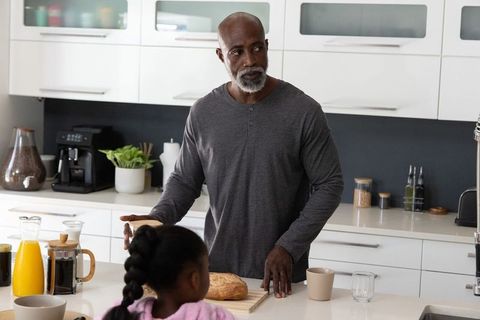 Senior african american man preparing breakfast with daughter in modern bright kitchen