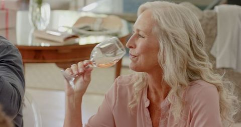 Senior Woman Enjoying Drink at Celebration Gathering Indoors
