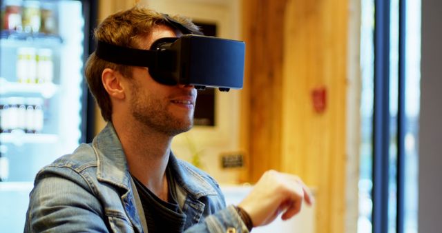 Man wearing VR headset in indoor setting. Perfect for technology blogs, VR experience promotions, gaming industry advertisements, and articles about modern entertainment.