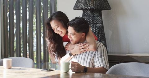 Couple sharing morning coffee and warm embrace at sunlit dining table
