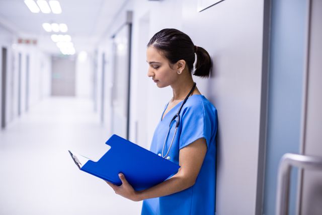 Female doctor reading reports in corridor of hospital
