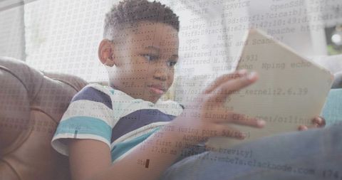 Child reading tablet on sofa with coding overlay technology concept for digital learning