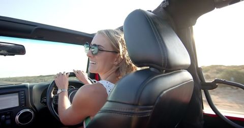 Smiling Woman Driving Convertible on Scenic Coastal Road Trip