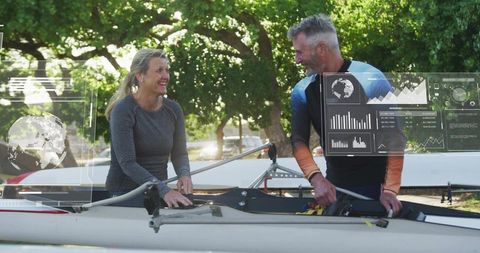 Middle-aged rowers adjusting scull rigging with hud analytics overlay for training and teamwork