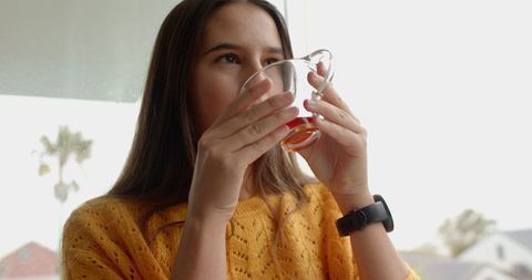Woman Enjoying Warm Beverage by Window in Cozy Setting