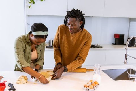 African american couple preparing dough on bright modern kitchen island baking at home