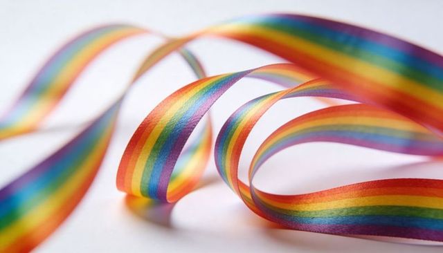 Looping rainbow satin ribbon curling into vibrant spectrum loops on white surface