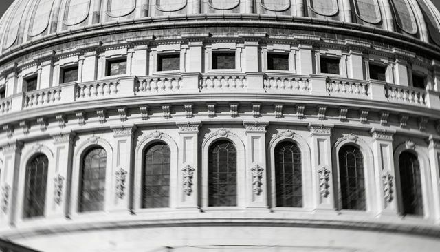 Curved neoclassical dome drum showing arched windows and stone balustrade in monochrome