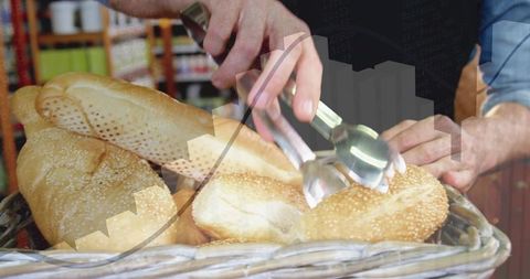 Bakery vendor picking sesame roll with tongs from wicker basket, retail bread display