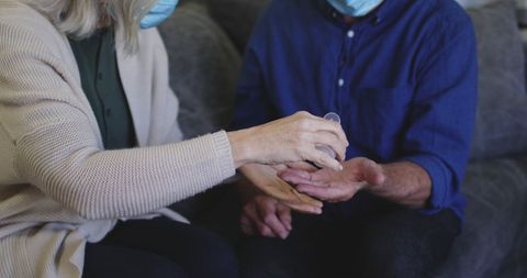 Senior couple in masks practicing hand hygiene together