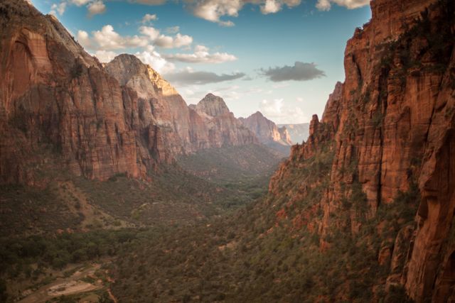 This photo showcases a breathtaking canyon landscape with rugged cliffs and a serene valley below, bathed in the warm light of the setting sun. Ideal for use in travel brochures, nature magazines, and inspirational posters highlighting the beauty of natural landscapes.