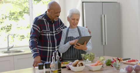 Senior Couple Preparing Vegetables with Tablet in Modern Kitchen