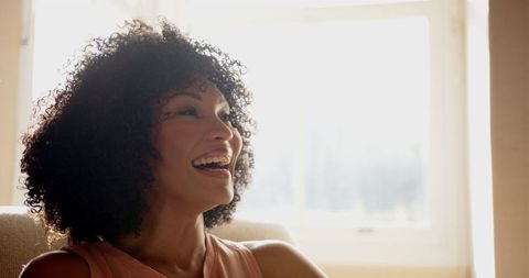 Joyful Woman with Curly Hair Sunlit Inside Home