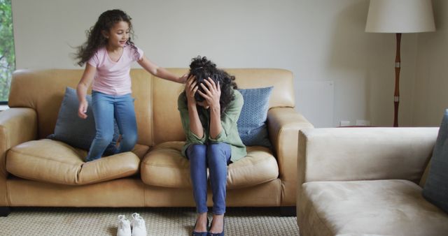 Biracial daughter jumping on the sofa, mother is stressed - Download Free Stock Photos Pikwizard.com