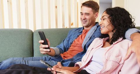 Happy Couple Relaxing Together on Sofa with Smartphones