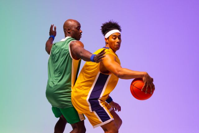 Two african american male basketball players in action, in purple and green light, copy space. Athlete, sport, competition, confidence and fitness concept.