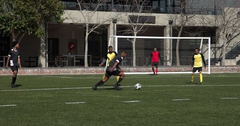 Intense Soccer Match with Players Running After Ball on Green Field