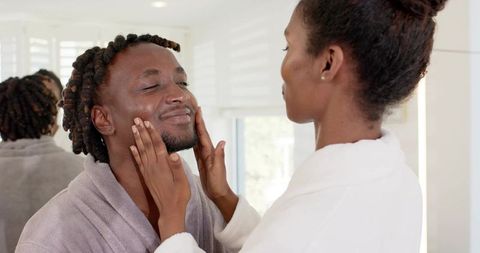 African american couple practicing morning skincare routine together in bright bathroom