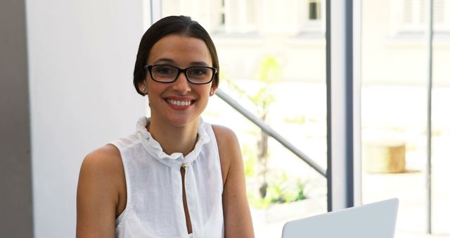 Confident Woman Wearing Glasses Smiling at Workplace - Download Free Stock Images Pikwizard.com