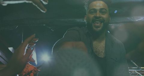 Smiling Male Singer Reaching for Microphone While Engaging Crowd on Intimate Club Stage