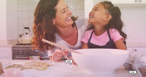 Laughing mother and daughter baking together in kitchen