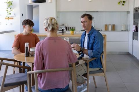 African family having casual breakfast conversation at modern sunlit kitchen dining table