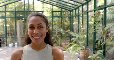 Smiling woman enjoying tranquility in bright greenhouse