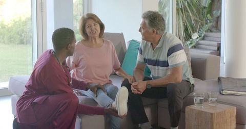 Healthcare professional assisting senior couple at home