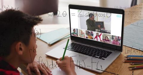 Asian boy engaged in virtual math lessons with online tutor via laptop