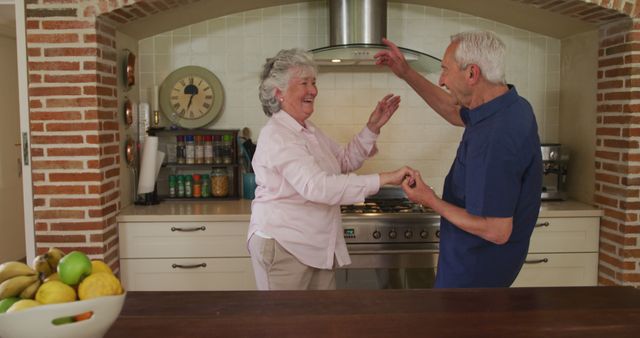 Happy caucasian senior couple having fun dancing in kitchen. Senior lifestyle, togetherness, fun, romance and retirement, unaltered.