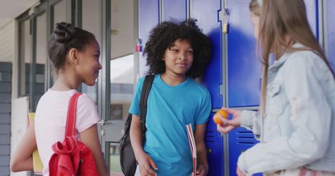 Diverse Schoolgirls Socializing by Lockers in School Corridor
