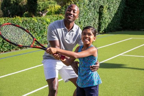 Father Enhancing Daughter's Tennis Skills in Outdoor Coaching Session