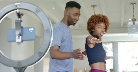 Home fitness coaching with ring light recording: personal trainer guiding posture and form