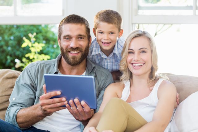 Portrait of parents and son using digital tablet in living room at home