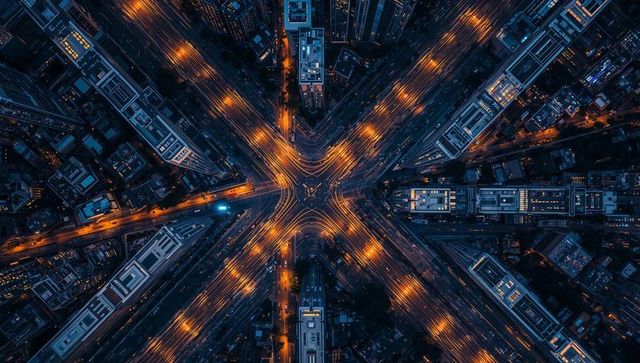 Aerial night intersection glowing with golden light trails and symmetrical urban grid