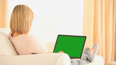 Relaxed Woman Using Laptop with Green Screen at Home